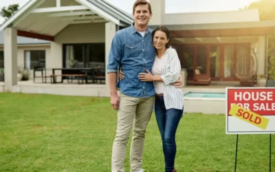 couple in front of a house with a sold sign
